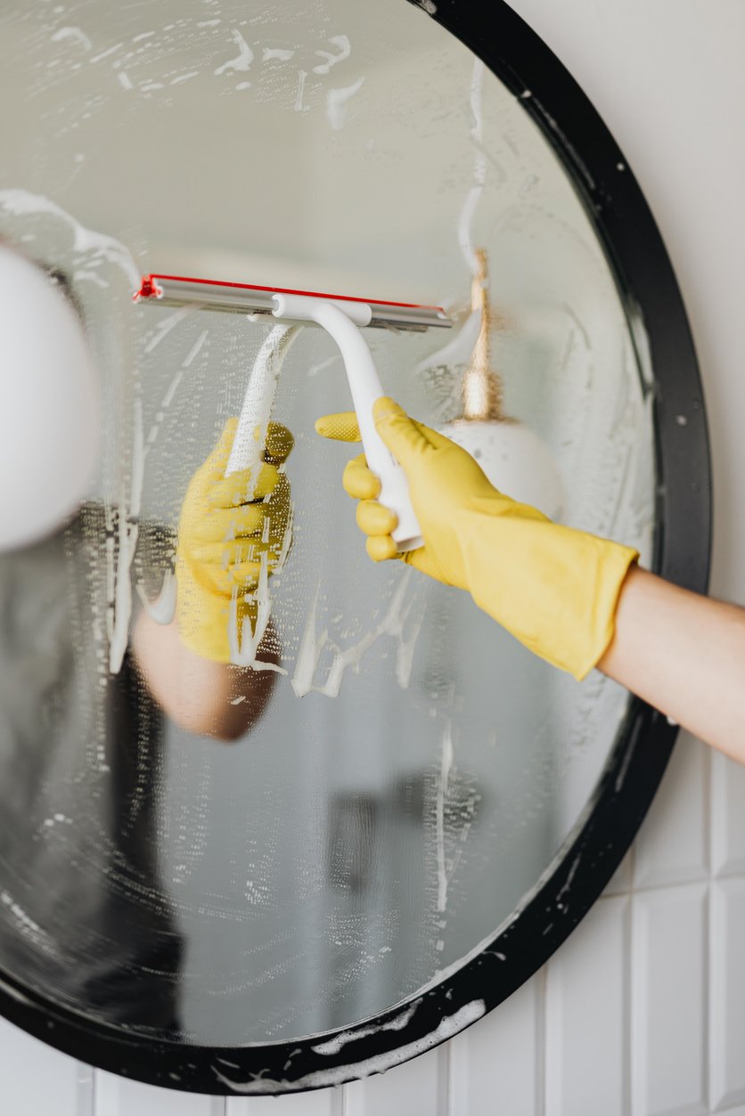 Anonymous man cleaning mirror in bathroom